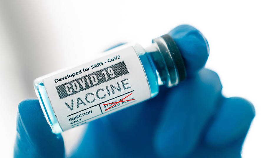 A gloved hand holds bottle of vaccine dosage 