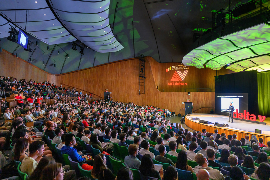 The auditorium is packed as the audience watches a speaker.