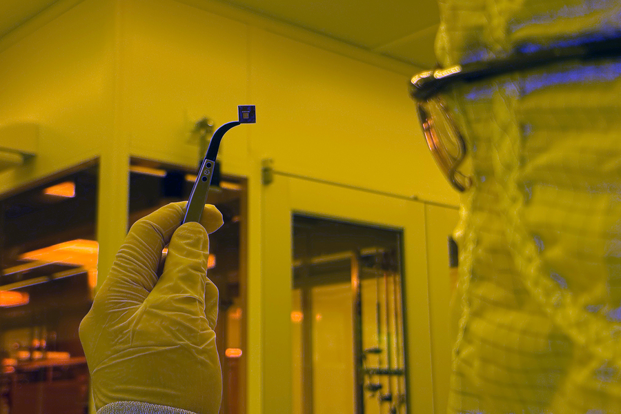 A researcher holding a small chip containing hundreds of devices
