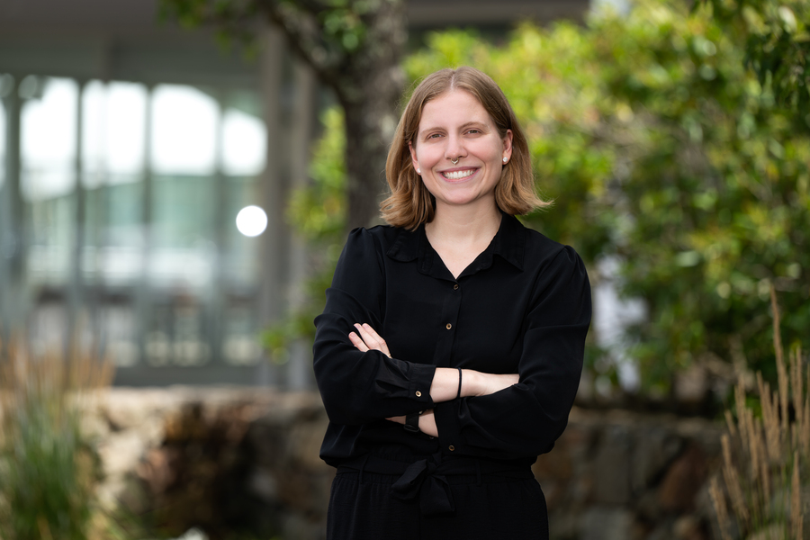 Anna Raymaker portrait photo, with trees and a glass facade in the background. 