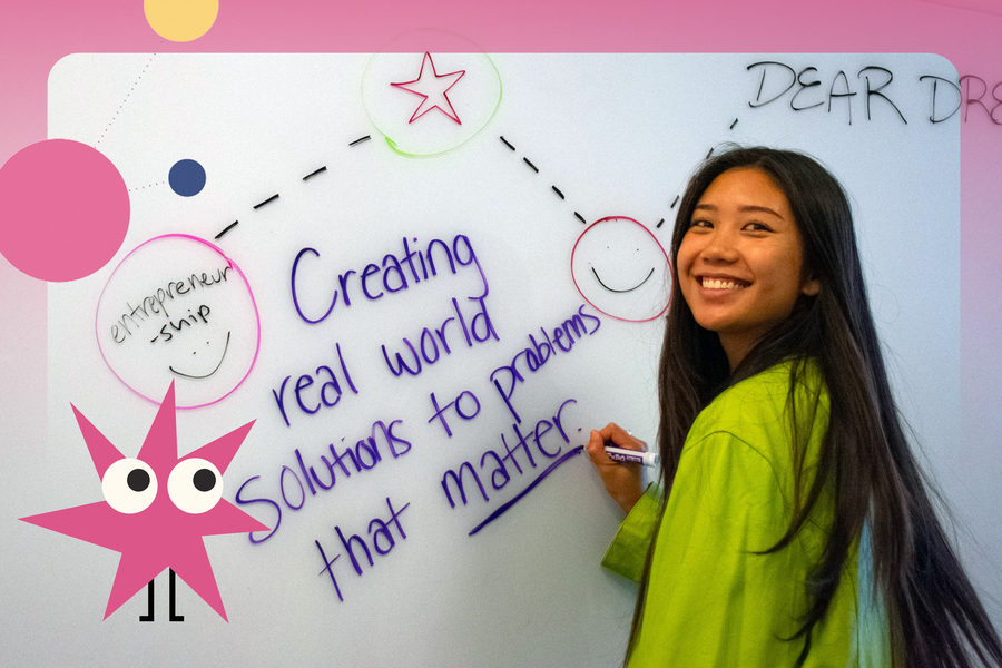 A young woman smiles while at a whiteboard as she writes, “Creating real world solutions to problems that matter.”