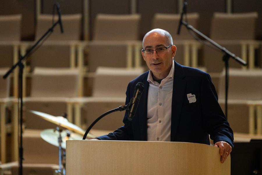 David Kaiser speaks at a lectern, a bank of empty seats behind him