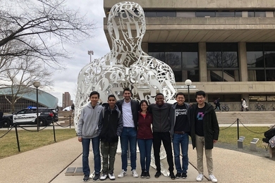 Seven MIT chess team students standing in front of a white metal sculpture