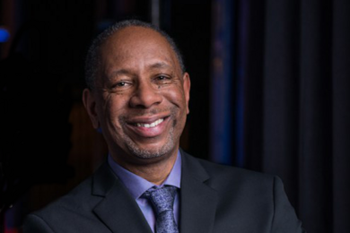 Portrait photo of Ceasar McDowell smiling and wearing a suit
