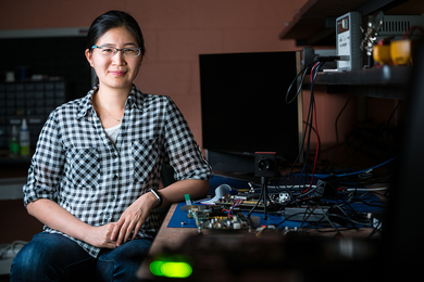 Photo of Vivienne Sze sitting at a table with lots of electronic equipment