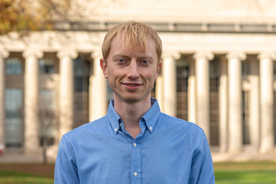 Photo of Anders Hansen standing outside, on MIT's Killian Court, with background of Building 10's columns