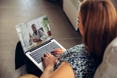 Photo of a young woman watching a doctor speak through a video on her laptop