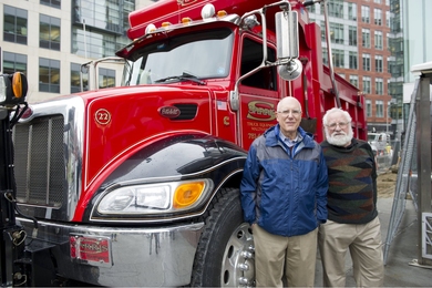 Photo of two men standing in front of a semi-truck cab
