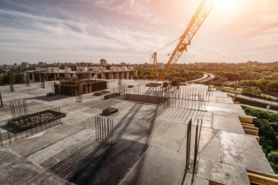 Photo of a concrete building under construction overlooking a highway at dusk