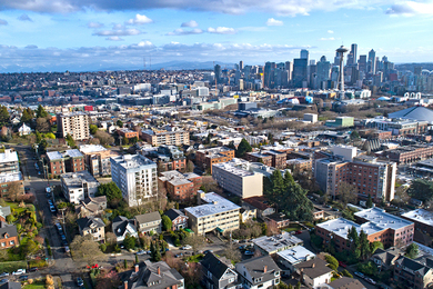 Aerial photo of the Seattle skyline, featuring a collection of skyscrapers along with the Space Needle and suburban buildings in the foreground
