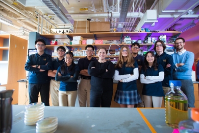 question for research paper Group portrait of nine high school students and an MIT instructor standing together in lab.