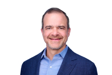 Portrait of Jeff Wilke in a sport coat and open-collared shirt against a plain white background