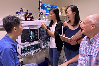 Four researchers surround a mass spectrometer