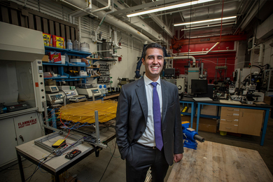 Zack Cordero, wearing a suit and tie with his hand in his front pocket, poses in his lab