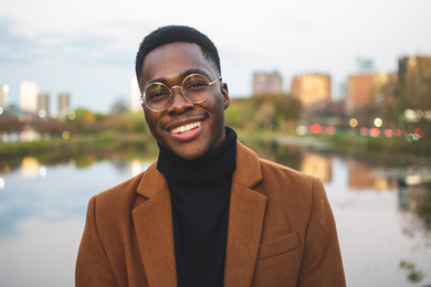 Ayomikun Ayodeji, smiling, in front of a river and city skyline