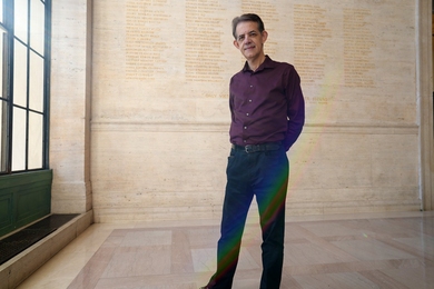 Renaud Fournier stands by French doors in MIT's Lobby 10, which is floor-to-ceiling tan marble