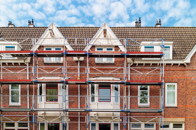 Scaffolding sits in front of red brick rowhouses in Amsterdam being renovated