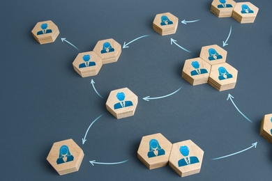 Photo illustration showing groupings of one, two, or three hexagonal blocks with icons of men and women on them, sitting on a gray surface with arrows showing connections between the groups
