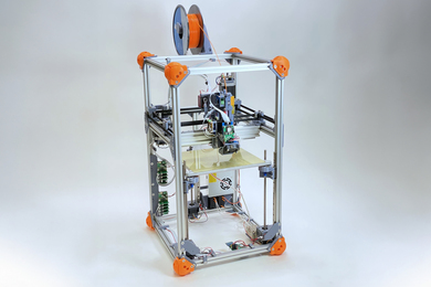 A 3D printer with two-tier cube structure while revealing open wires and circuitry.