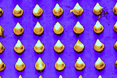 A colorized microscopic view shows the cone-shaped microneedles laid on out a grid, in yellow, on a purple surface.