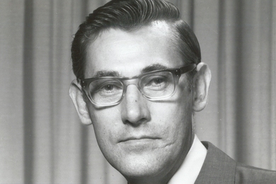 Black and white 1950s-era portrait of David Lanning wearing a suit and tie against a curtained background