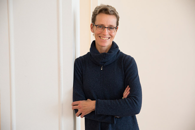 Portrait photo of Kate Brown leaning against a white door