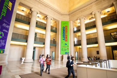 A few people walk through MIT’s Lobby 7, an atrium with three floors