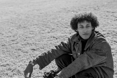 Grayscale photo of Nolen Scruggs seated on a field of grass