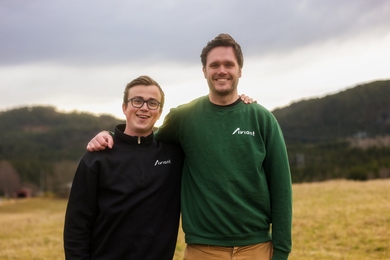 Øie Kolden and Lars Erik Fagernæs, both wearing Aviant shirts, pose together on a grassy field on a cloudy day.