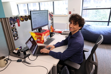 Allan Shtofenmakher smiles for a photo while sitting at an office desk