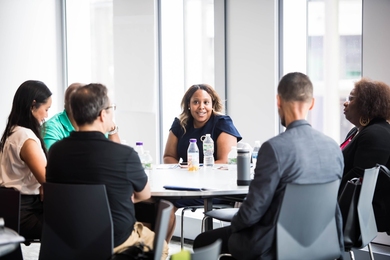 what is program research and development A diverse group of 6 people sit at a round table by a window