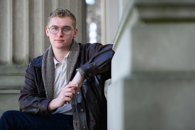 Liam Hines seated outdoors with architectural columns around him