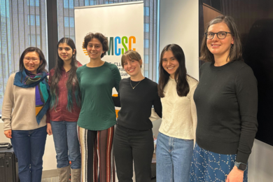 Six women link arms and pose for a picture.