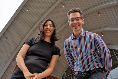 Anna Huang and Eran Egozy pose under a curved overhang