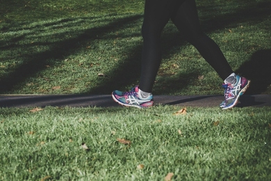 Photo of the legs of a person walking on a path through grass