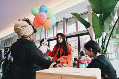 Two women talking, one holding a bunch of colorful balloons