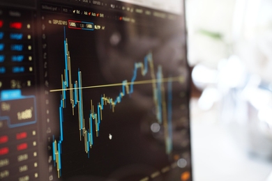 Photo of a line graph on a computer screen, representing data analysis being performed in an office-like setting.