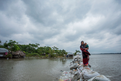 Woman and children walk over sandbag embankment in Bangladesh