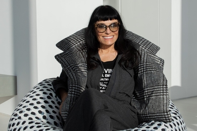 Norma Kamali, dressed in black, sits on a black-and-white polka-dot beanbag chair