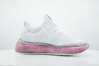 White running shoe with a transparent midsole filled with pink and black particles