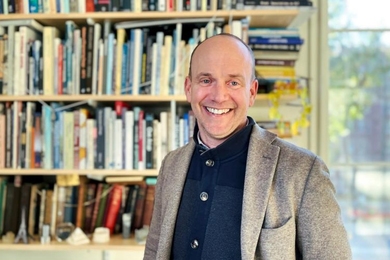 John Ochsendorf standing in front of a bookcase