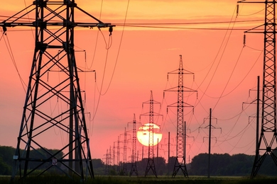 Photo shows silhouette of high-voltage power lines and towers during sunset