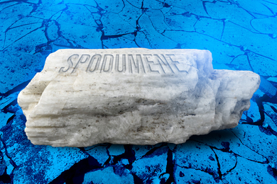 A rock is made of labeled “Spodumene” on blue rocky background.