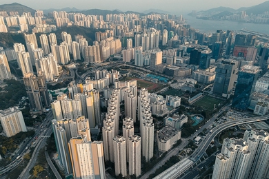 Aerial view of a dense part of Hong Kong with towering skyscrapers and intricate roadways.