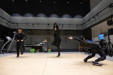 Three people dance in motion-capture suits indoors