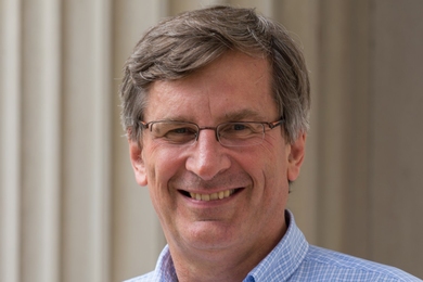 Bolek Wyslouch, wearing glasses and a light-blue button-down shirt, stands in front of the MIT pillars