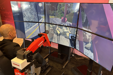 A person sits and operates a training machine and stares at six screens showing an excavator digging up a road.