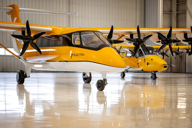 Two Electra airplanes, compact and yellow, in a hangar.