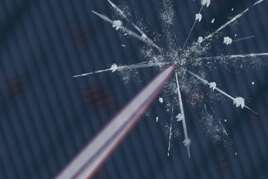 A laser beam hits a surface, causing a glass-like crack with white particles ejected.