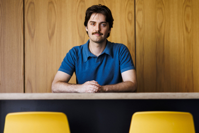 Gage Coon portrait, seated, with two yellow chairs in foreground.